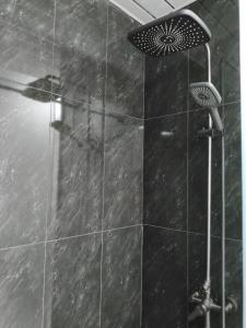 a shower with a black tiled wall and a black umbrella at Alvina 2 apartment hotel in Tsaghkadzor