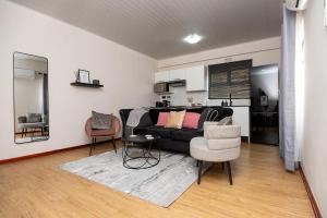 a living room with a black couch and two chairs at D12 Premier Stay in Gaborone