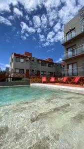 einem Pool mit Stühlen vor einem Gebäude in der Unterkunft Cepas de Mar Resort & Wine in Las Gaviotas