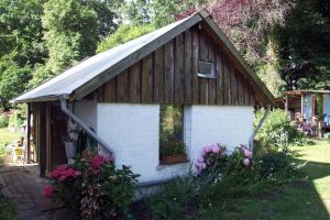a small house with a wooden roof and flowers at Lovely Garden House in Bramsche in Bramsche +4 photos