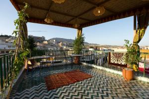 a balcony with tables and chairs and a view of a city at Riad Qobbat Zaouïa in Fez
