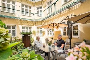 two people sitting at a table in a garden at Hotel Josefshof am Rathaus in Vienna +86 photos
