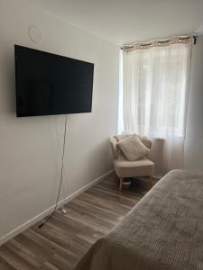 a bedroom with a tv on the wall and a chair at Pause Campagne 1 in Gadencourt