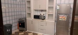 a kitchen with white cabinets and a microwave and a refrigerator at النخيل للشقق المفروشة in Al Madinah