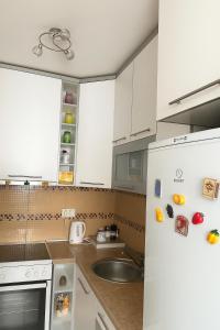 a white kitchen with a sink and a refrigerator at Apartman Bloom in Sarajevo
