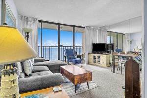 a living room with a couch and a table at Cozy Oceanfront Condo with Heated Pools & Views in Kure Beach