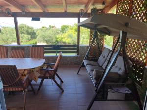 a porch with a swing and a table and chairs at George's family friendly maisonette with great exterior in Drosia