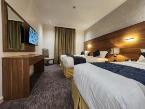 une chambre d'hôtel avec deux lits et une télévision à écran plat dans l'établissement فندق رواء العزيزية, à La Mecque 35 autres photos