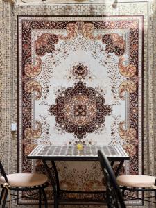 a table with chairs in front of a wall at Riad Shama in Rabat