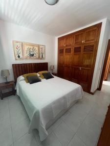 Schlafzimmer mit einem großen weißen Bett und Holzschränken in der Unterkunft Casa Maresía in Playa Honda