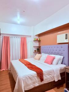 una camera da letto con un grande letto con lenzuola bianche e cuscini rosa di Sunvida tower SM cebu a Cebu City