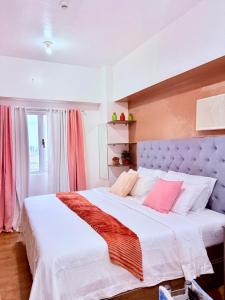una camera da letto con un grande letto con lenzuola bianche e cuscini rosa di Sunvida tower SM cebu a Cebu City