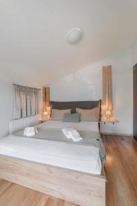 une chambre avec un grand lit blanc avec deux lampes dans l'établissement Kalliston - Meteora, à Kalambaka