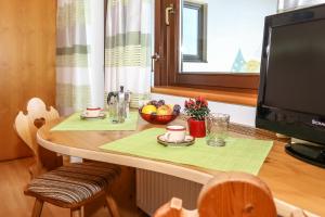 a table with a bowl of fruit and a television at Alps Residence in Nova Ponente