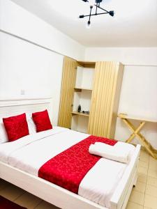 a bedroom with a large bed with red pillows at Koshy Cosy Homes in Narok