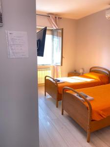 two beds in a room with a tv on the wall at Afficamere Mattia Mottola 1 in Fiumicino