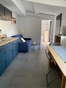 a kitchen with blue cabinets and a blue couch at Maison La Hume climatisée avec piscine et terrasse in Gujan-Mestras
