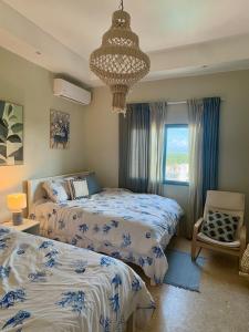 a bedroom with two beds and a chandelier at Juan dolio Penthouse, beach access 3BR Salitre Tower front of Club Hemingway in Juan Dolio