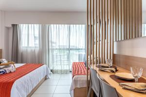 a hotel room with a bed and a table and a window at Makia Beach Experience- Flat 202D in Ipojuca +100 photos
