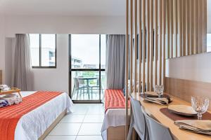 Cette chambre d'hôtel comprend un lit et une table avec des assiettes. dans l'établissement Makia Beach Experience- Flat 202D, à Ipojuca 83 autres photos