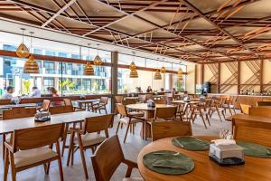 un restaurant avec des tables et des chaises et des gens en arrière-plan dans l'établissement Makia Beach Experience- Flat 202D, à Ipojuca