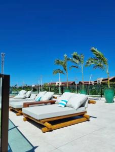 - une rangée de lits sur une terrasse avec des palmiers dans l'établissement Makia Beach Experience- Flat 202D, à Ipojuca