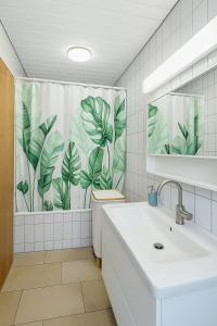 a bathroom with a toilet and a shower curtain with leaves at Bright furnished Studio with workspace and garden area near Zurich in Würenlos