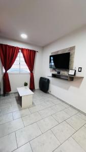 ein Wohnzimmer mit einem Flachbildfernseher an der Wand in der Unterkunft Casa Huerquen in Neuquén