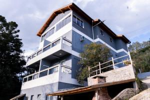 a blue and white building with a tree at Vista da Serra. in Gramado