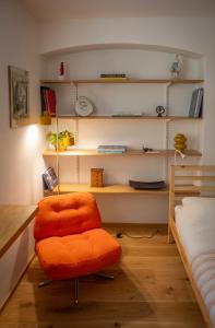 an orange chair in a room with a bed at Cosy Studio on Wagner street, Riga Old Town in Rīga