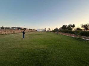 two people standing in a large grass field at C-69 Dreamland, Luxury 4BHK farm with private swimming pool , 1 acre garden in Bhundsi