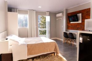 a bedroom with a bed and a desk and a television at Vista da Serra. in Gramado