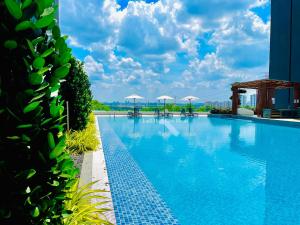 ein großer Pool mit Sonnenschirmen auf einem Gebäude in der Unterkunft Jim&Mie Cozy Homes 3R2BR at MIRAI Residence UKM GMI Kajang in Kajang