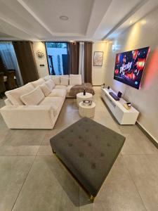 ein Wohnzimmer mit weißen Möbeln und einem Flachbildfernseher in der Unterkunft DELYA Maria in Abidjan
