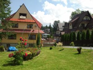 a house in a yard with flowers in a yard at Pokoje u Małgorzatki in Murzasichle