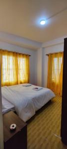 1 dormitorio con 1 cama grande y cortinas amarillas en The River View Crescent, en Kurseong