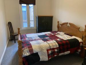 a bedroom with a bed with a quilt on it at Grand logement chaleureux in La Tuque