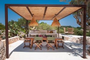 a wooden pavilion with a table and chairs on a patio at Trulli Moranera in Cisternino