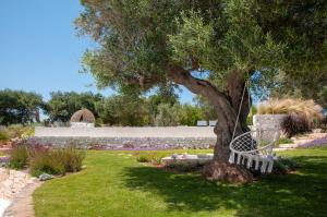 a swinging bench under a tree in a garden at Trulli Moranera in Cisternino