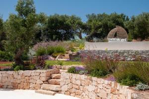 a garden with a stone retaining wall and a stone wall at Trulli Moranera in Cisternino
