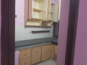 a kitchen with wooden cabinets and a black counter top at Home Stay in Vrindāvan
