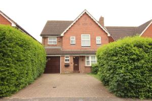 a brick house with a garage and two large bushes at Spacious 4 Bed Home near Elizabeth Line, perfect for Contractors, Families & Groups in Romford