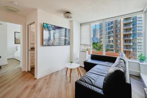 a living room with a couch and a large window at Cozy Urban Living! 2 mins from BC place, private parking ! in Vancouver