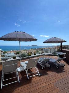 eine Terrasse mit Stühlen und Sonnenschirmen auf einem Dach in der Unterkunft Formia Bellevue in Formia