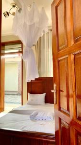 a bedroom with a bed with a canopy and a mirror at Safari Hotel Lyantonde in Lyantonde
