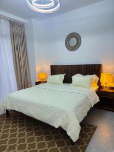 Un dormitorio con una gran cama blanca con dos lámparas. en The Luxury Home Company, en Kigali