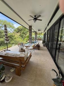 a screened in porch with a ceiling fan and chairs at Villa Montemar Ocean and Mountain Views Elevated 1200 FT with Wifi in Platanillo