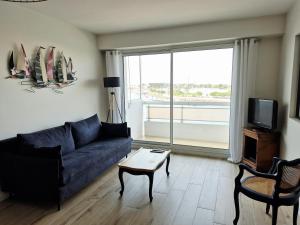 a living room with a blue couch and a tv at Appartement sur Port - 78m2 Balcon in Saint-Gilles-Croix-de-Vie