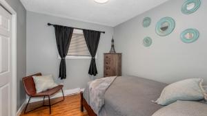 een slaapkamer met een bed, een stoel en een raam bij Knockan Hill Rentals - Ground Floor Suite in Victoria