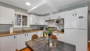 een keuken met witte kasten, een tafel en een koelkast bij Knockan Hill Rentals - Ground Floor Suite in Victoria